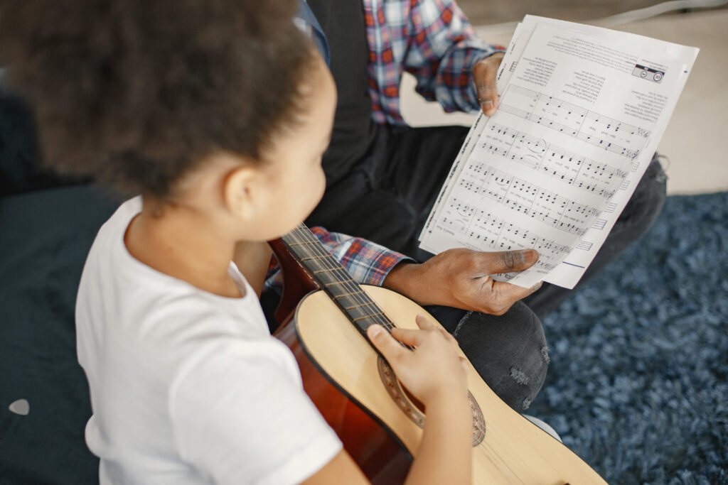African father teaches his daughter to play guitar